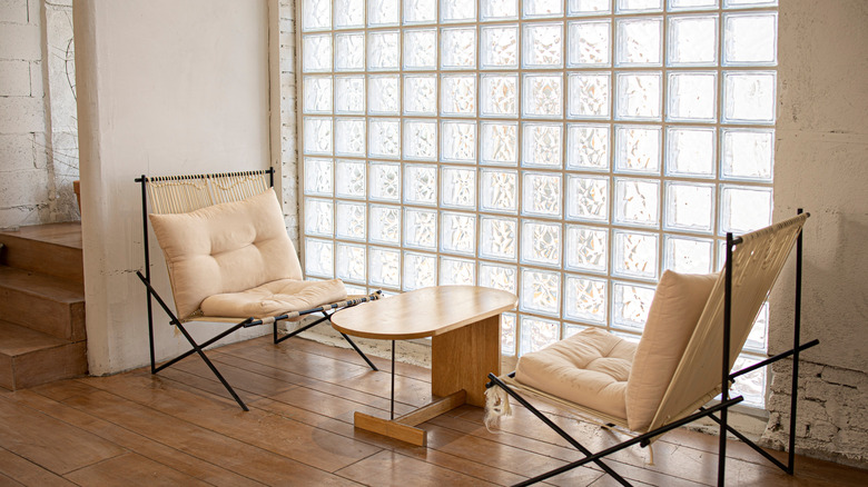 Tan chairs and table in front of glass block wall