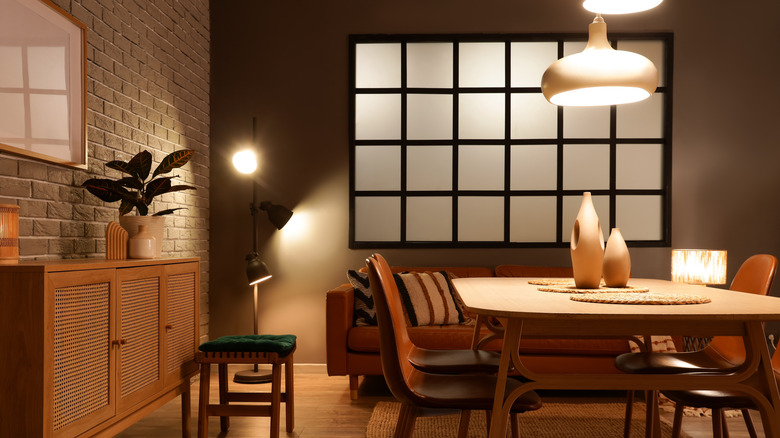 Unique pendant lights hang over a modern dining table, chairs, and leather sofa