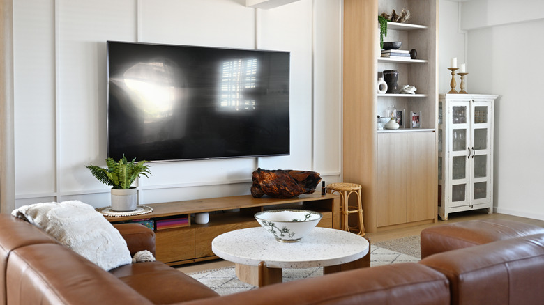 Large television on the wall in a modern living room with brown leather sofa