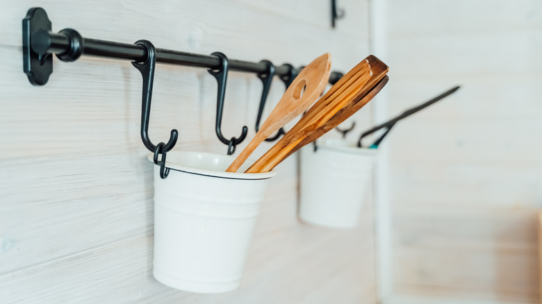Utensils hanging in white containers on a wall organizational system