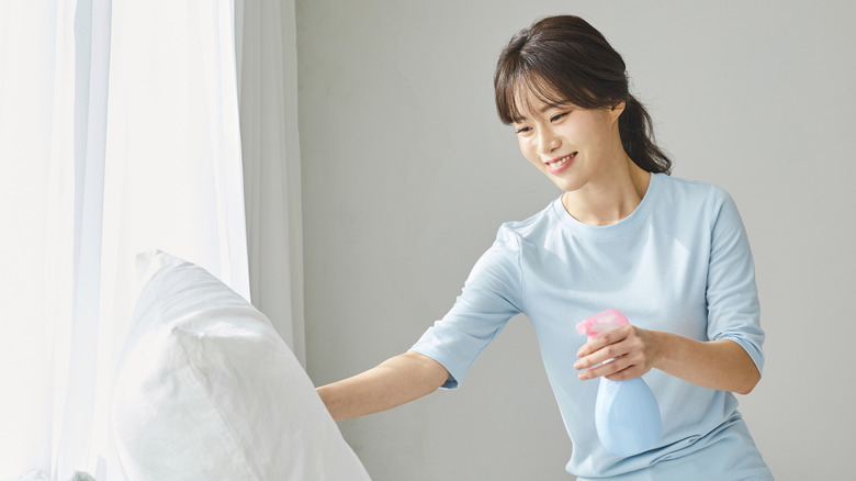 Woman spraying pillow with cleaning solution
