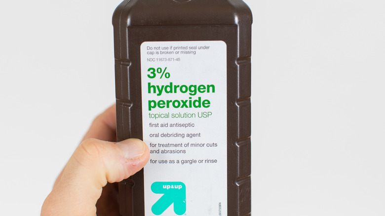 holding bottle of hydrogen peroxide