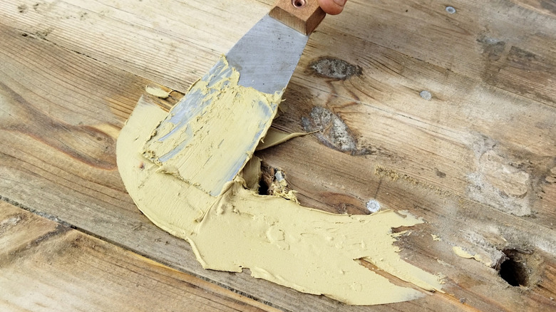 Applying putty to holes in damaged deck