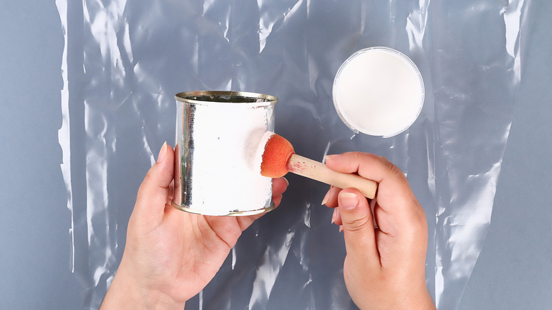 A hand painting an empty soup can