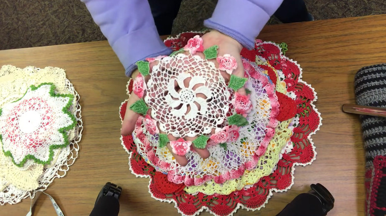 Person holding up a flower-themed vintage doily