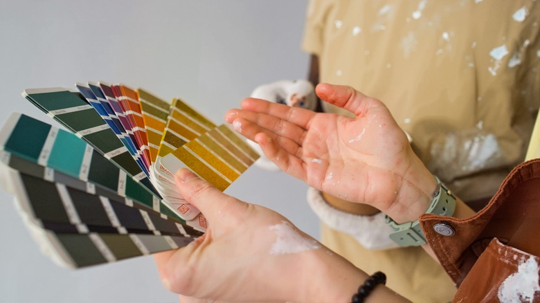 hands holding color swatches of paint