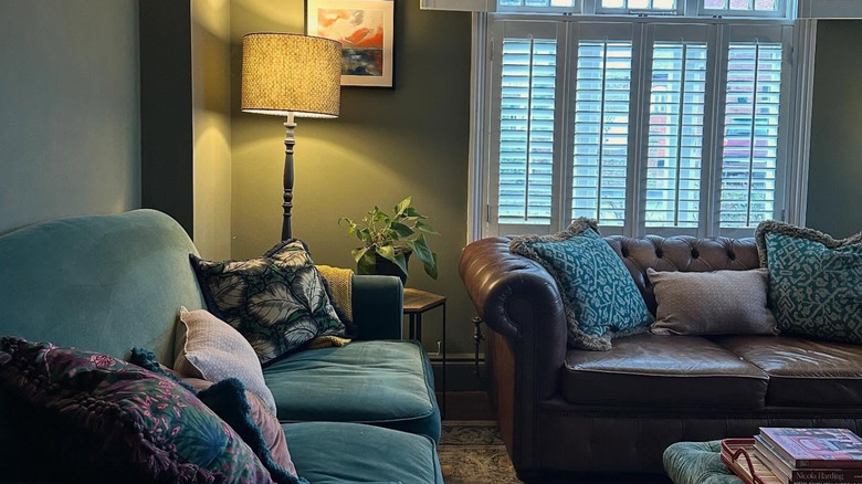 A living room with olive green walls and neutral accents