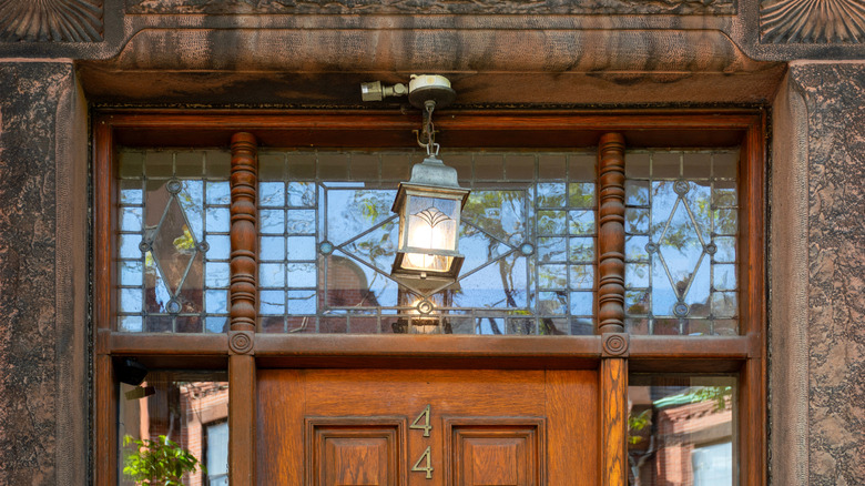 A leaded transom window is shown above the wooden door of a historic home