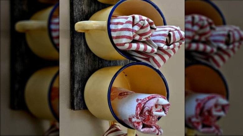 Mugs mounted to wood board holding tea towels