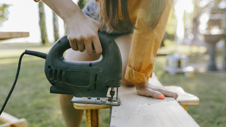 A person cutting a board with a saw