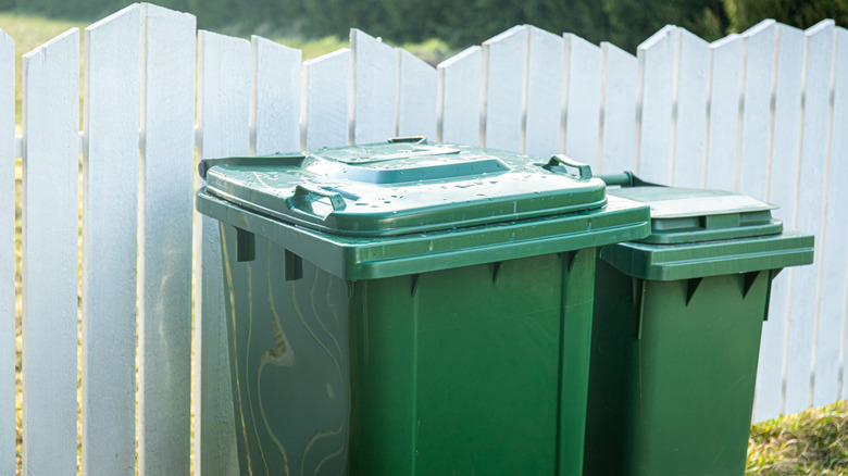 Garbage cans hidden behind a wooden fence