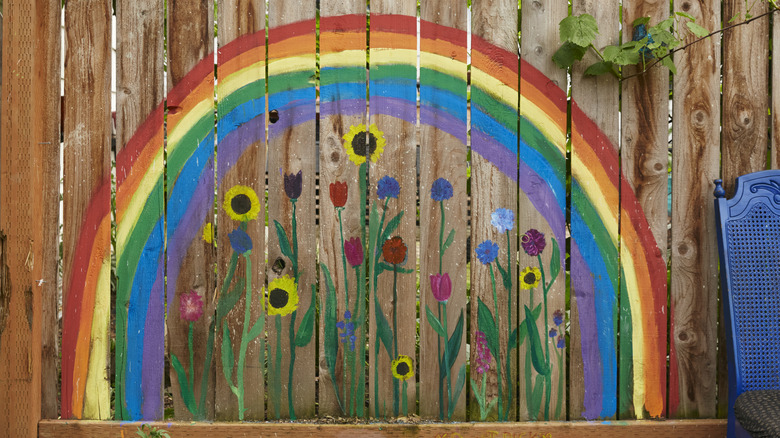 A privacy fence painted with a rainbow and flowers