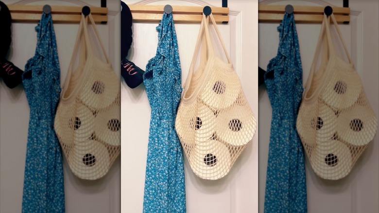 Toilet paper rolls hanging in a mesh bag on a door frame