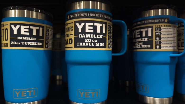 Three blue Yeti mugs on a shelf