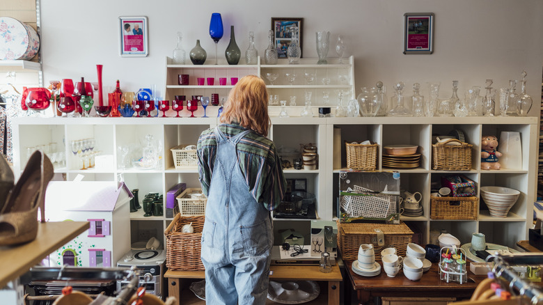 A person stands in front of shelves filled with thrift store finds