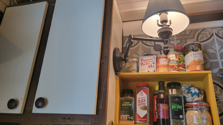 A DIY spice rack and task lighting add functionality to the thrifted bookcase kitchen cabinet