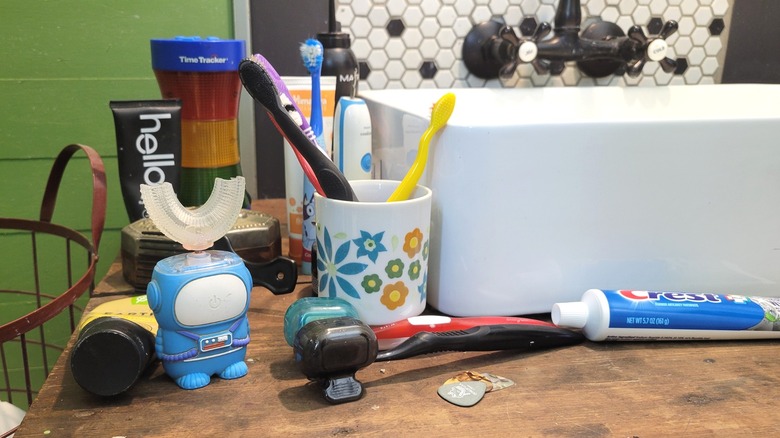 Toothbrushes, toothpaste, and other dental care items scattered across the bathroom counter