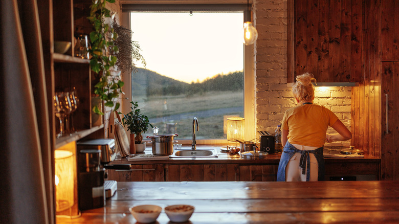Woman cooking in cozily lit rustic kitchen