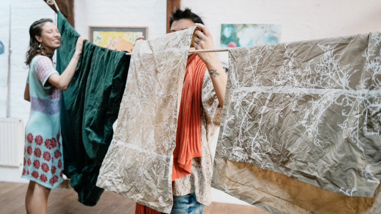 Two people hang clothes on a clotheline