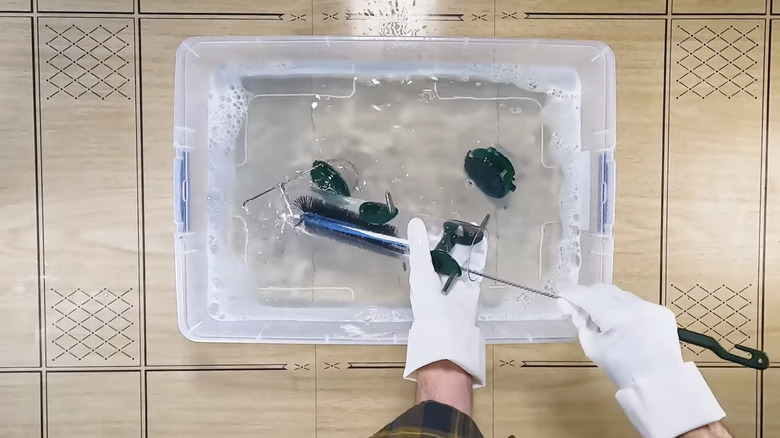 a person wearing gloves cleans a bird feeder