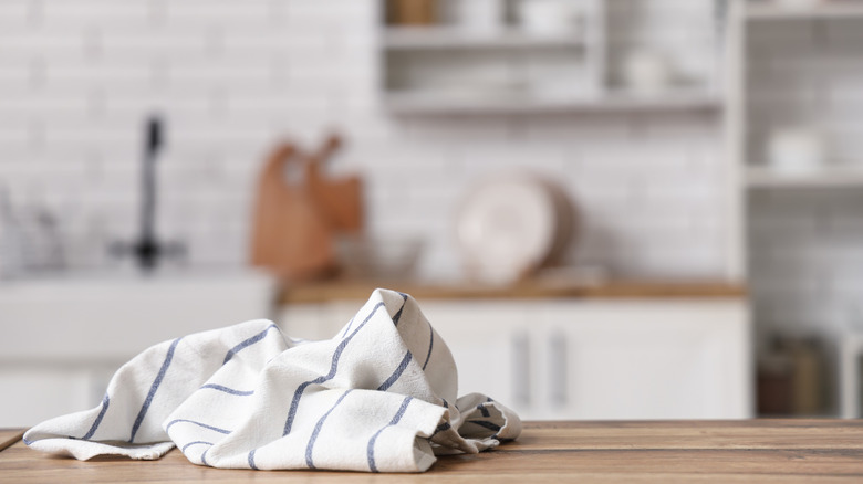 Close-up of a kitchen towel sitting on a counter with a sink and cabinets in the background