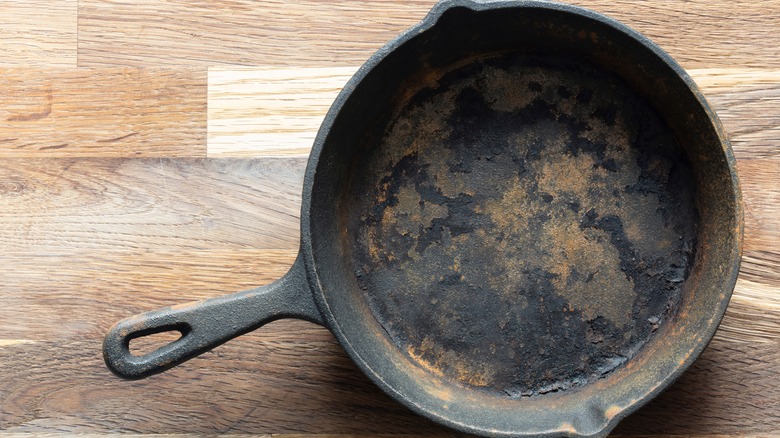 A rusty cast-iron pan on a wooden background.
