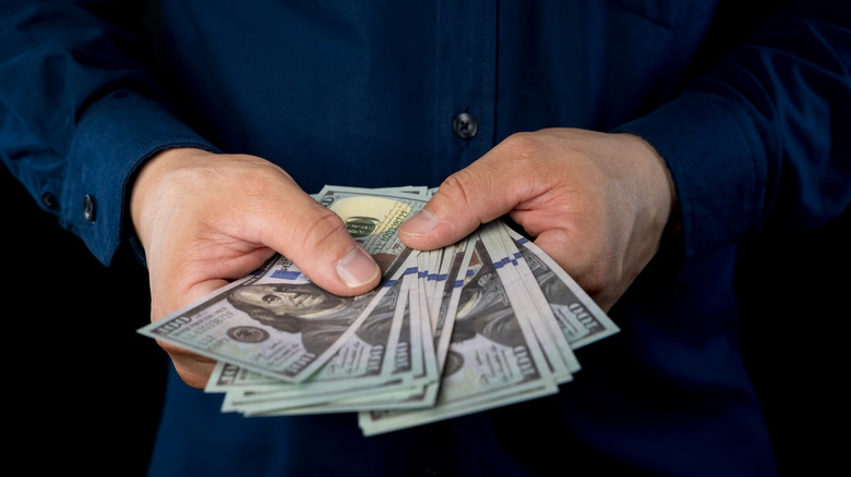 Person holding $100 bills