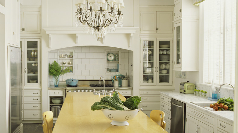 A large white kitchen with backsplash under a rounded stove hood