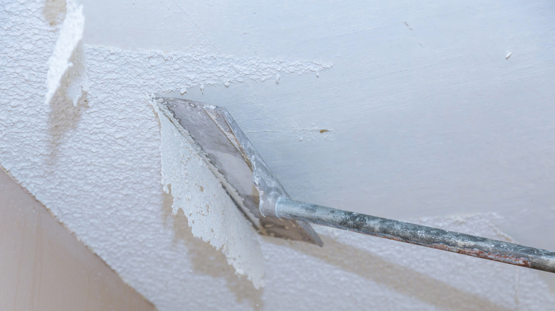 Removing popcorn ceiling with a scraper
