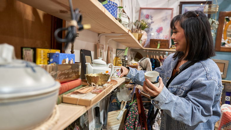 A person shopping for dishes in a thrift store.
