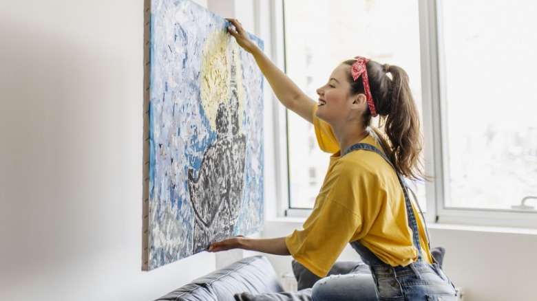 Woman putting custom art on wall to decorate living room