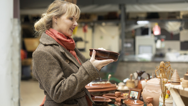 A woman smiles as she holds a vintage dish at a thrift store