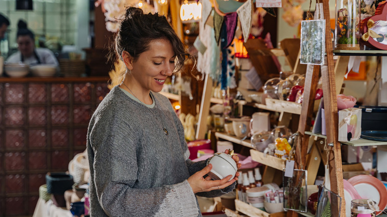 Woman shopping for pottery in thrift store.