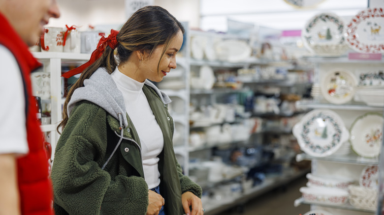 Woman smiling while looking at dishware in a store
