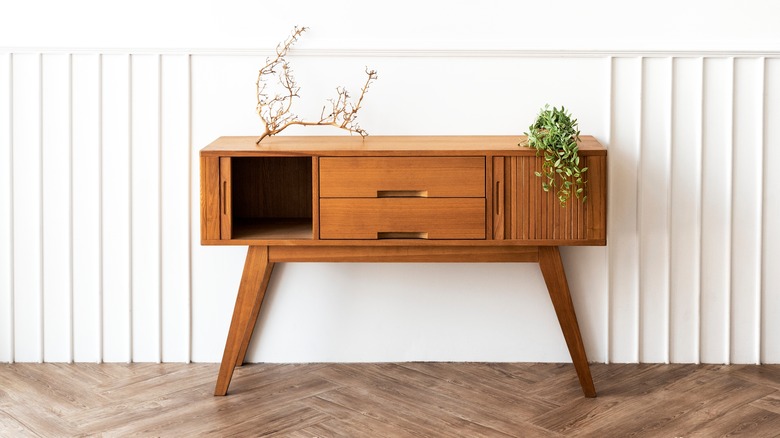 A midcentury modern table with a branch and plant on top