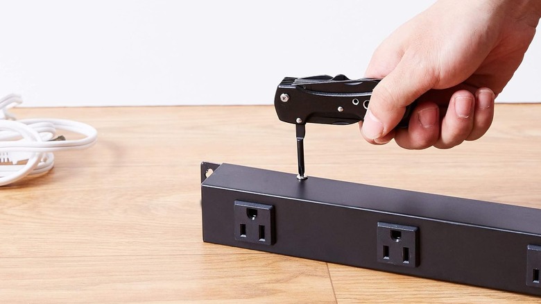 a person using the Amazon Basics multitool pocketknife to tighten a screw on an extension cord