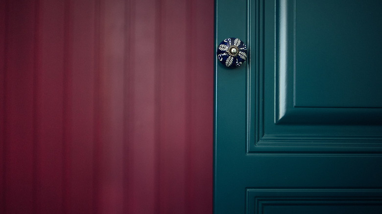 teal cabinet door against a deep magenta paneled wall