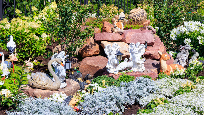 A flower bed with vintage angel and animal statues