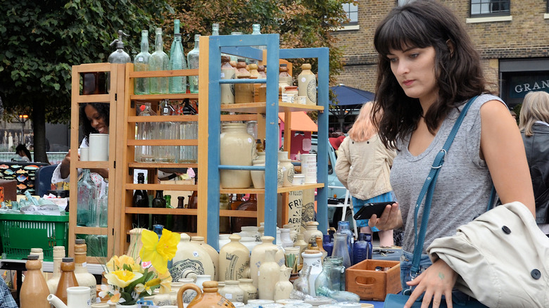 A woman looks at vintage cookware in a market