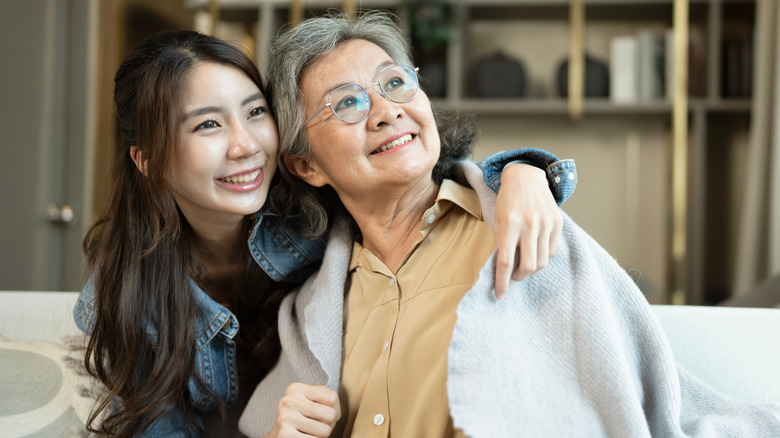 A young woman hugs her elderly grandmother as they both smile