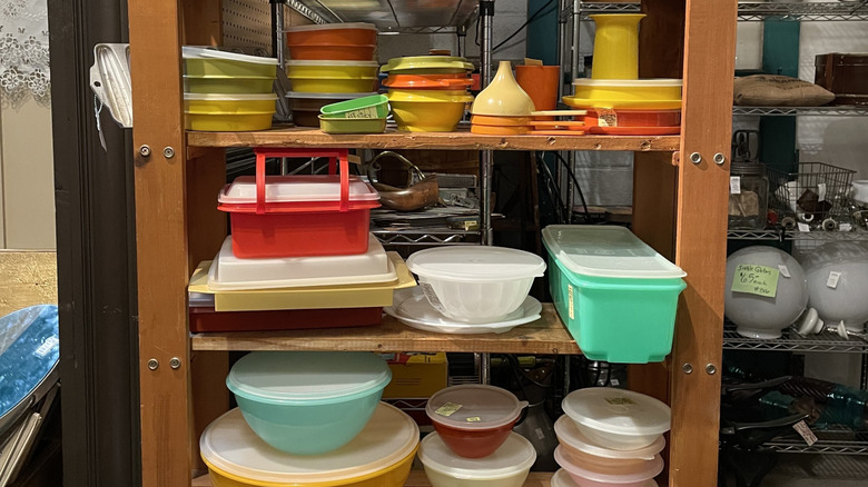 A shelf filled with vintage tupperware at a thrift store