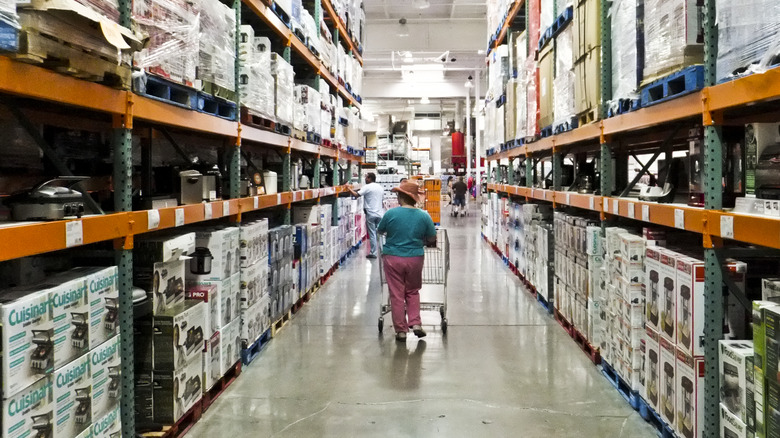 woman walking down the aisle in a costco store with cart