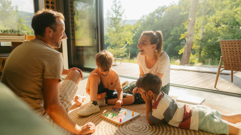 A family smiling while playing a game on the floor.