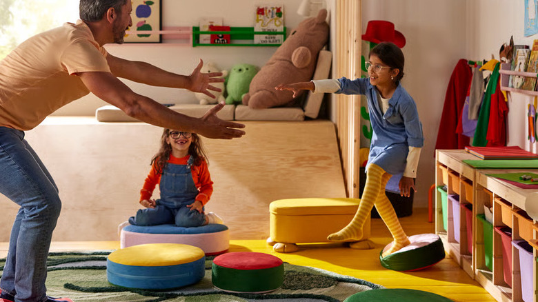 A parent and two children playing on IKEA's Grejsimojs Floor Cushions.