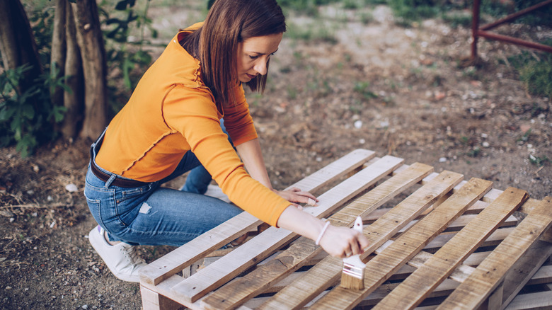 woman painting wood pallets