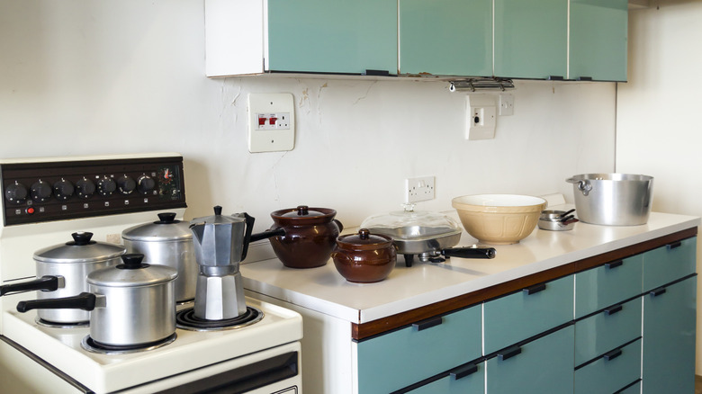 A white a green kitchen in the 1960s style.