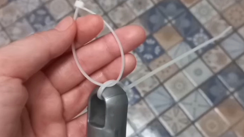 Man holding zip tie attached to a broom