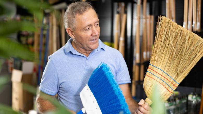 Man holding two brooms