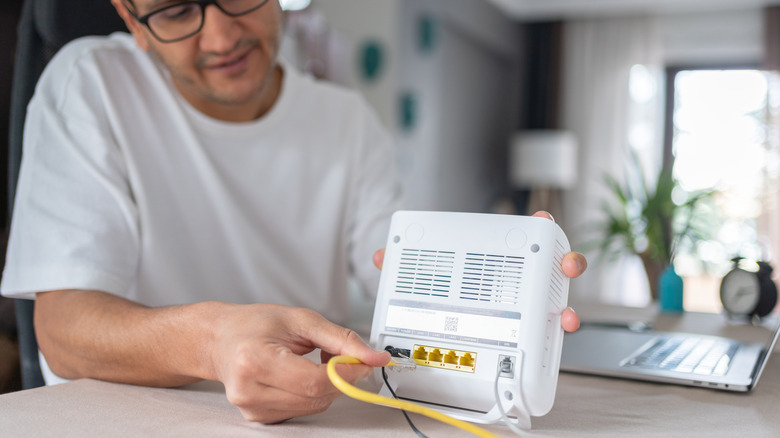 Man connecting cable to Wi-fi modem