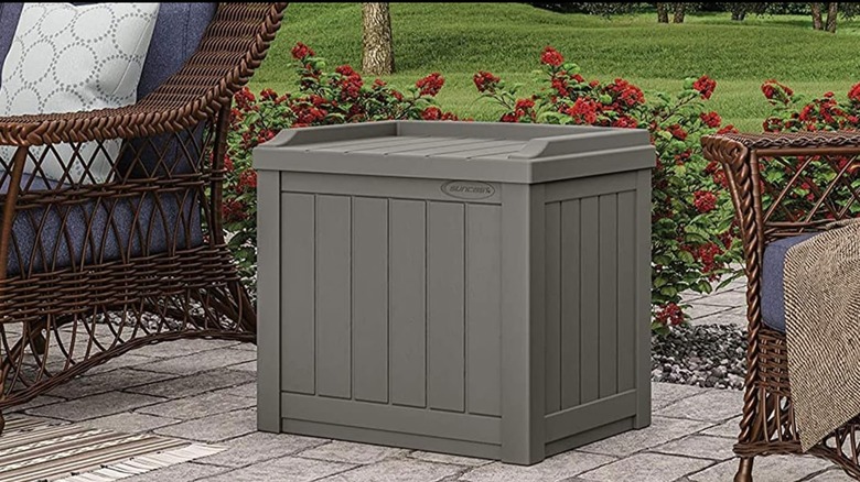 Suncast 22-Gallon Outdoor Storage Box on patio between wicker outdoor seats